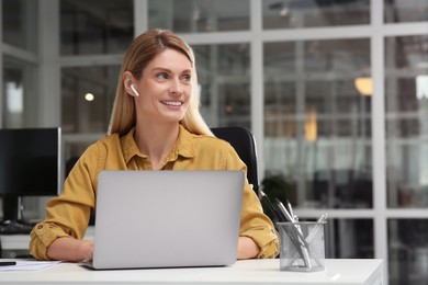 Woman working on laptop at white desk in office. Space for text
