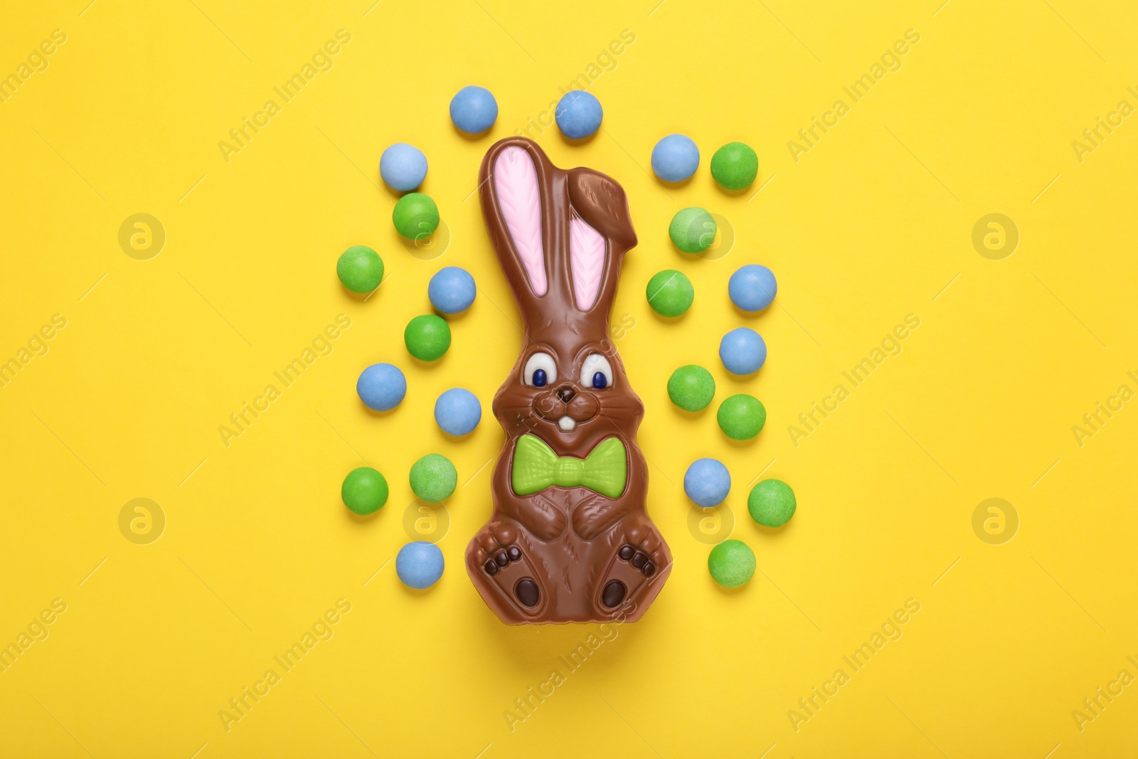 Photo of Chocolate Easter bunny and candies on yellow background, flat lay