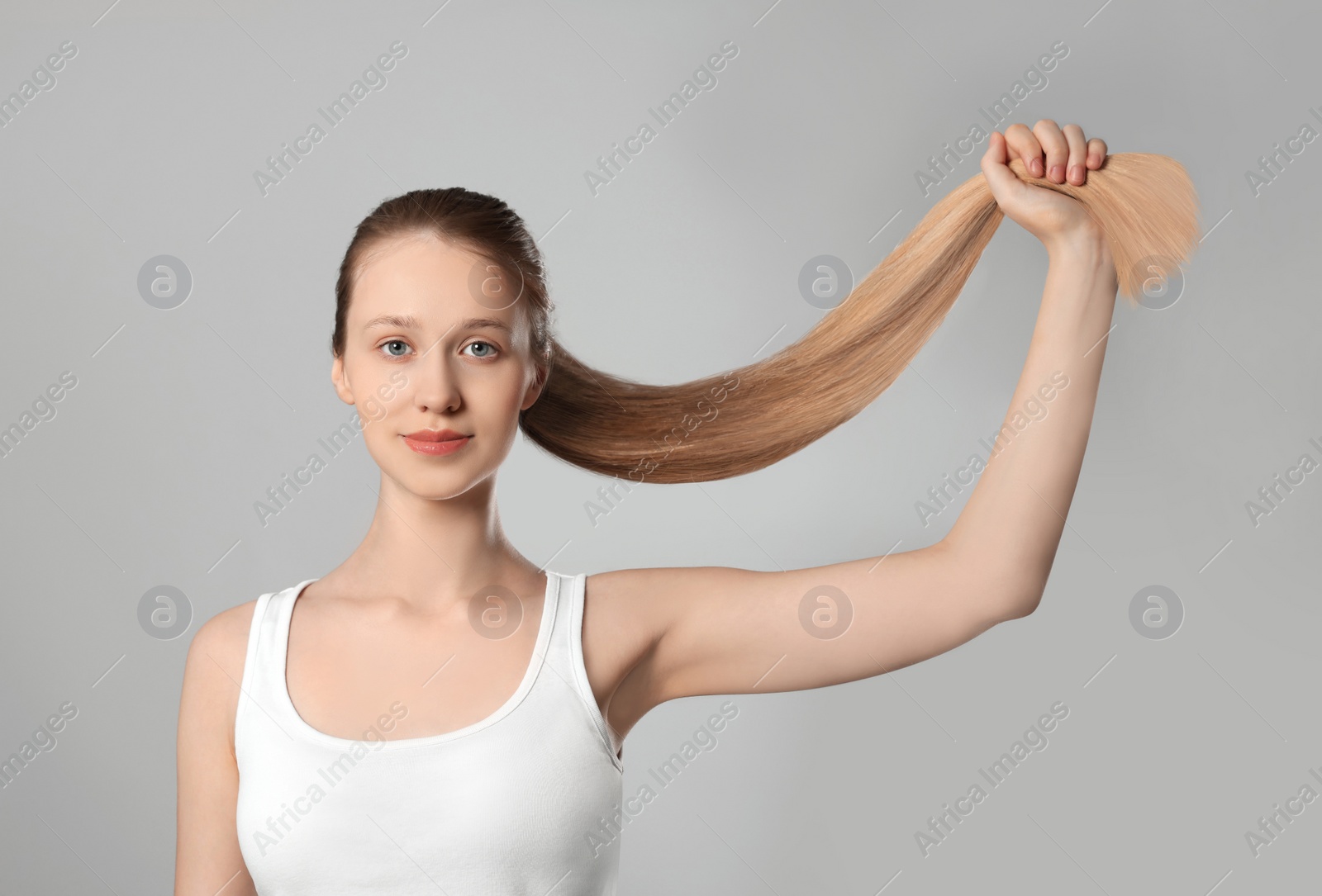 Photo of Teenage girl with strong healthy hair on light grey background