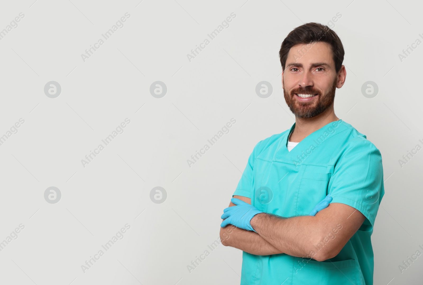 Photo of Happy nurse in medical uniform on white background, space for text