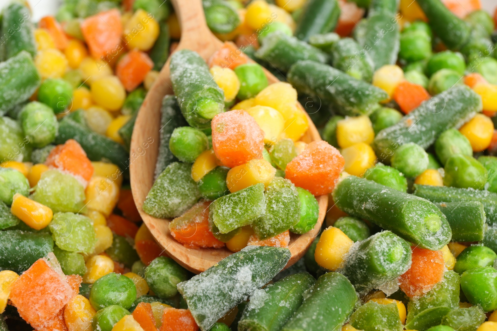 Photo of Mix of frozen vegetables and wooden spoon, closeup