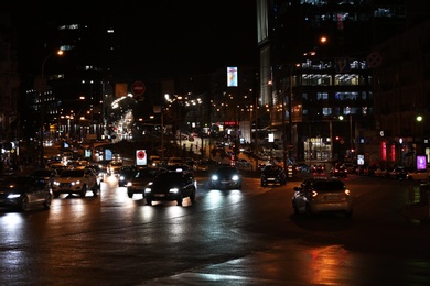 Photo of KYIV, UKRAINE - MAY 22, 2019: View of illuminated city street with road traffic and buildings