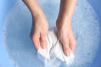 Top view of woman hand washing white clothing in suds, closeup