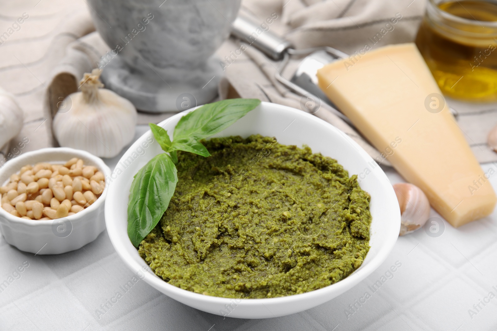 Photo of Bowl with tasty pesto sauce and fresh basil on white table, closeup