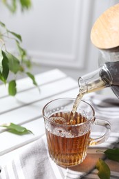 Photo of Pouring hot tea into cup on table, closeup