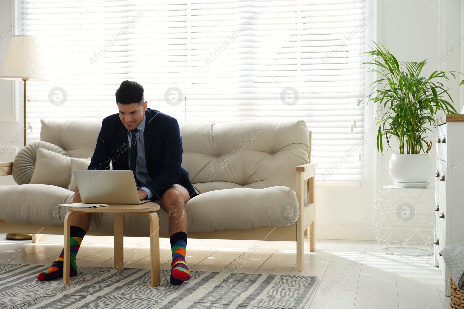 Photo of Businessman in jacket and underwear working on laptop at home