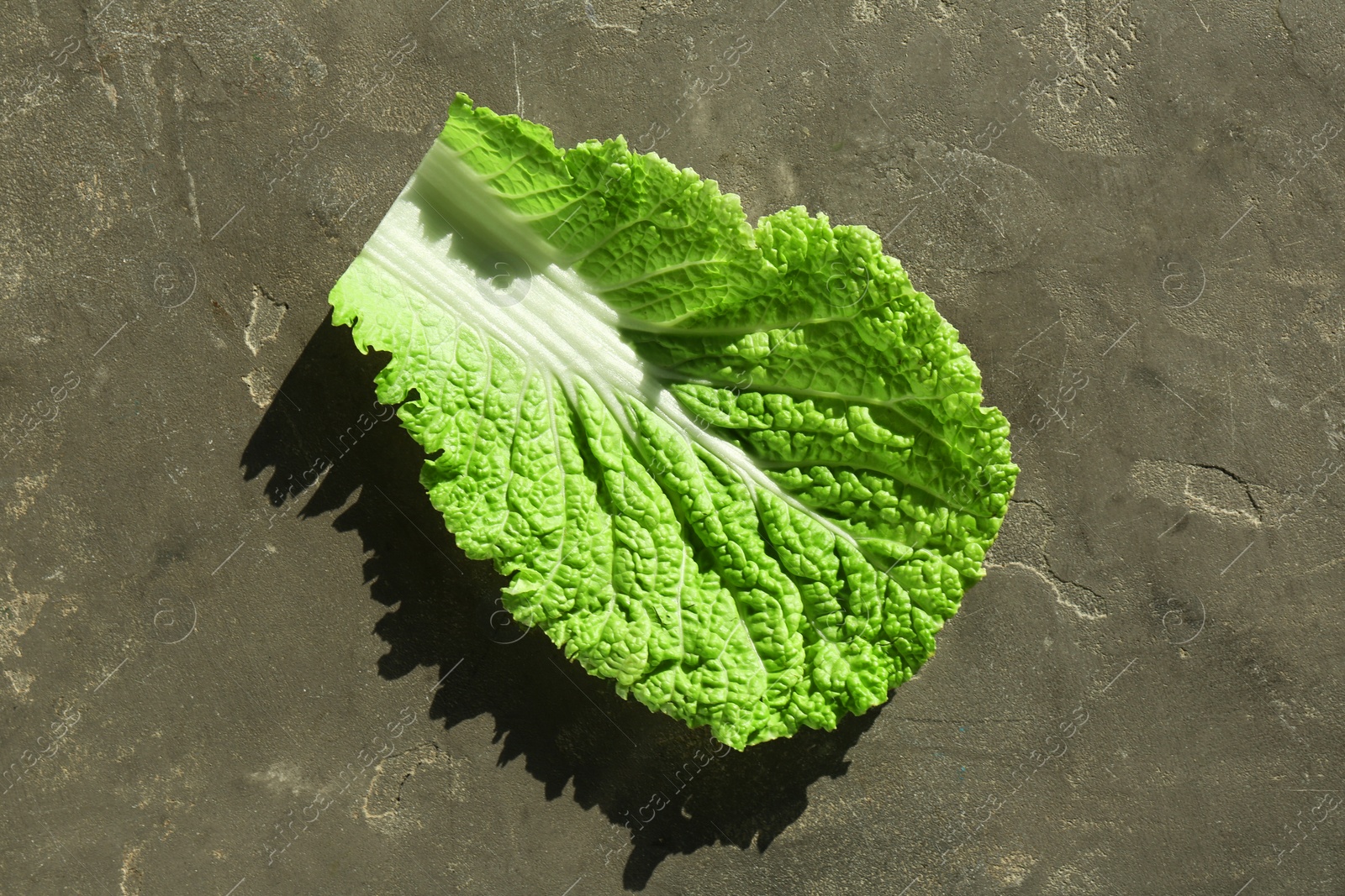 Photo of Fresh Chinese cabbage leaf on gray textured table, top view