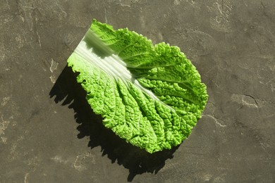 Photo of Fresh Chinese cabbage leaf on gray textured table, top view