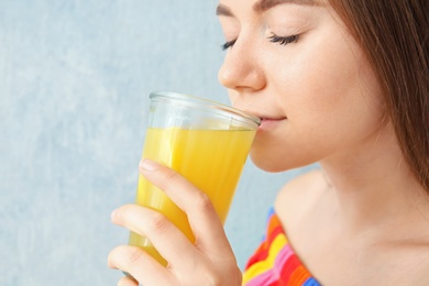 Photo of Young woman drinking lemon juice on color background, closeup