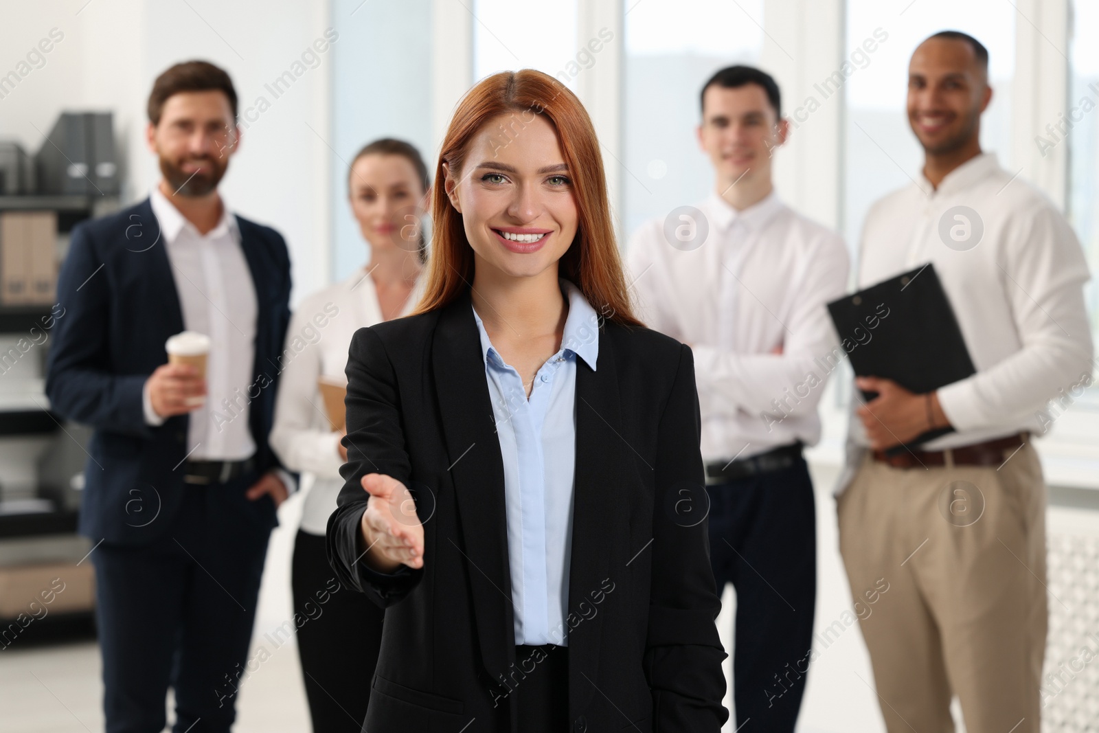 Photo of Group of people in office. Happy woman welcoming and offering handshake indoors