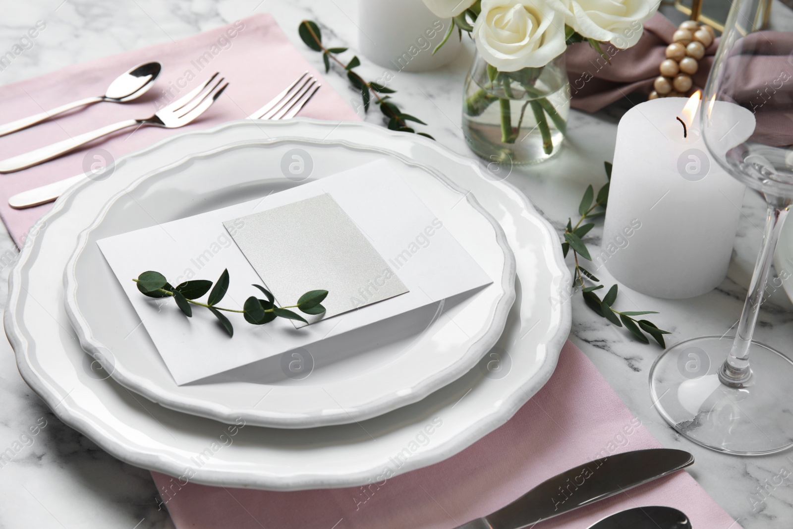 Photo of Elegant festive table setting with blank card on white marble background