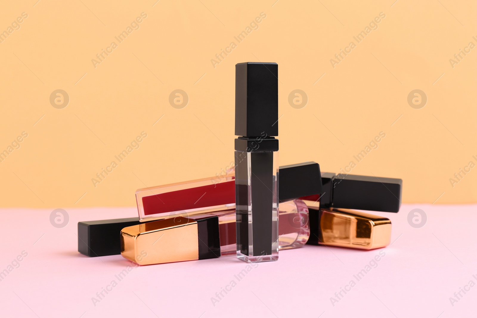 Photo of Many different lip glosses on color background