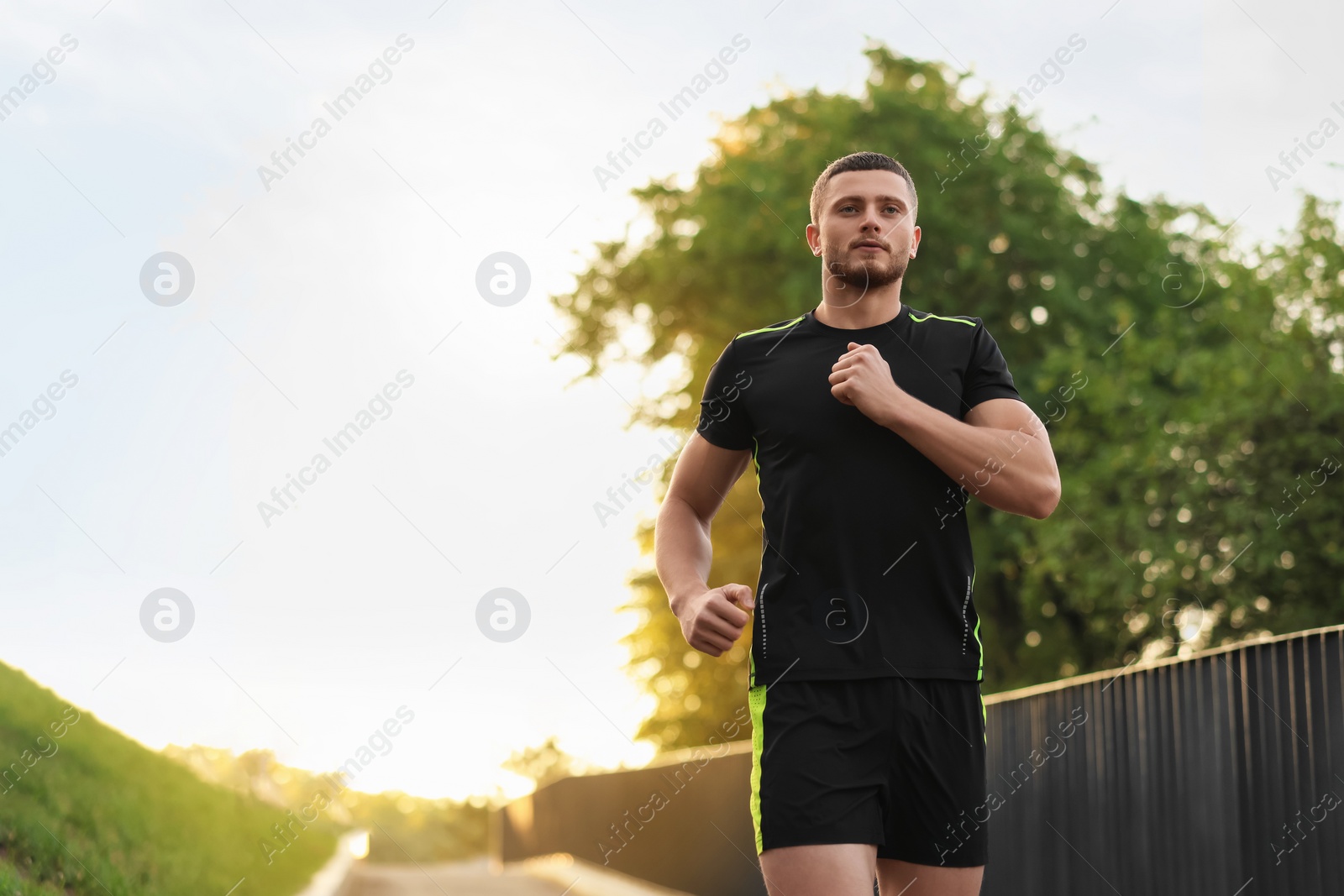 Photo of Attractive sporty man in fitness clothes jogging outdoors