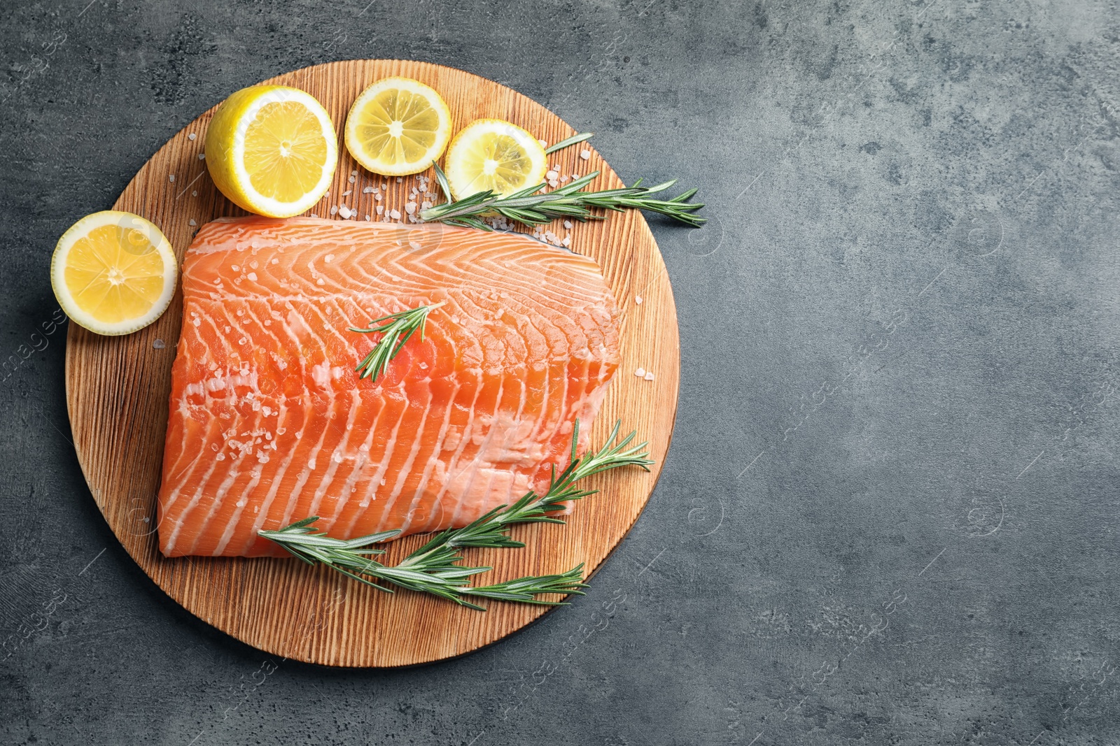 Photo of Wooden board with raw salmon and ingredients for marinade on grey background, top view