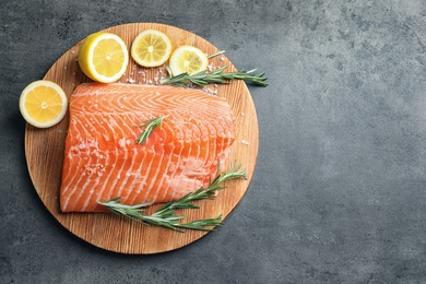 Photo of Wooden board with raw salmon and ingredients for marinade on grey background, top view