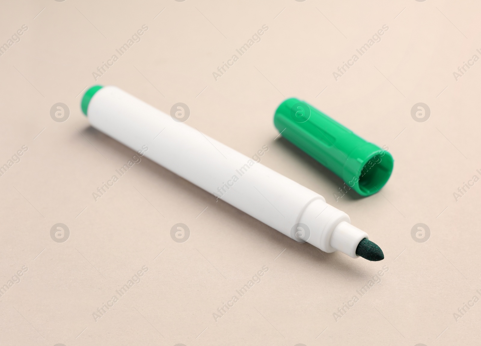 Photo of Bright green marker on beige background, closeup. School stationery