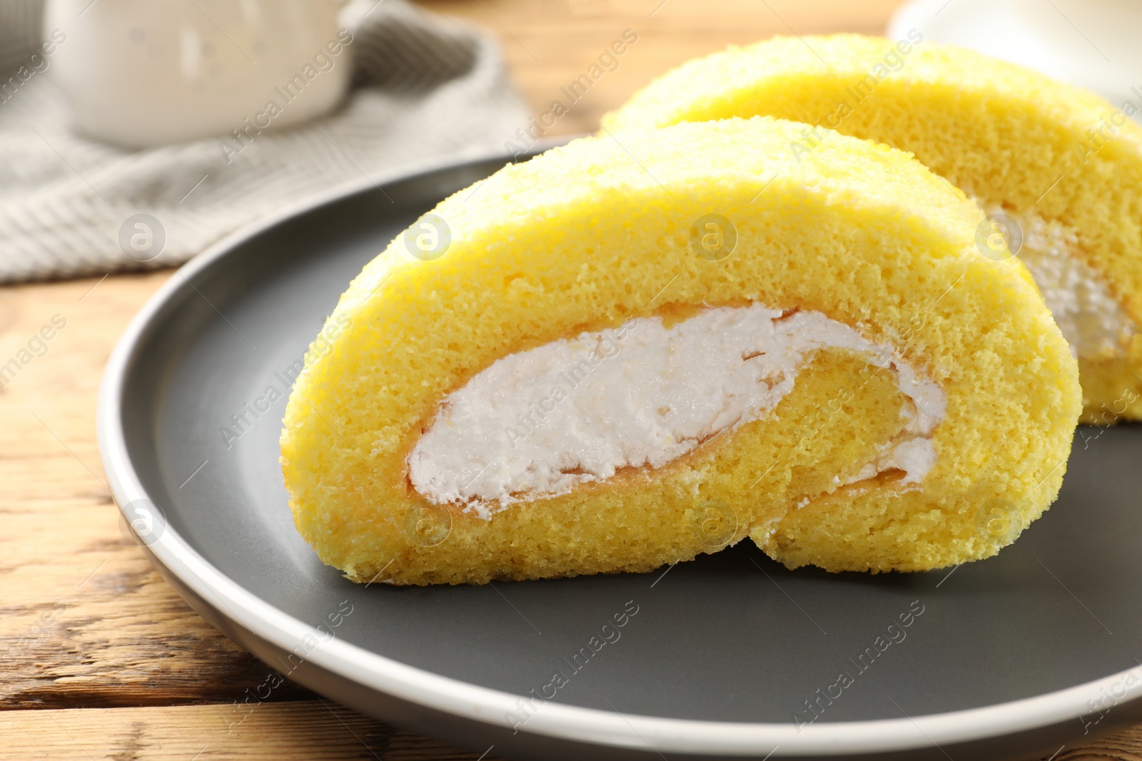 Photo of Delicious cake roll with cream filling on wooden table, closeup