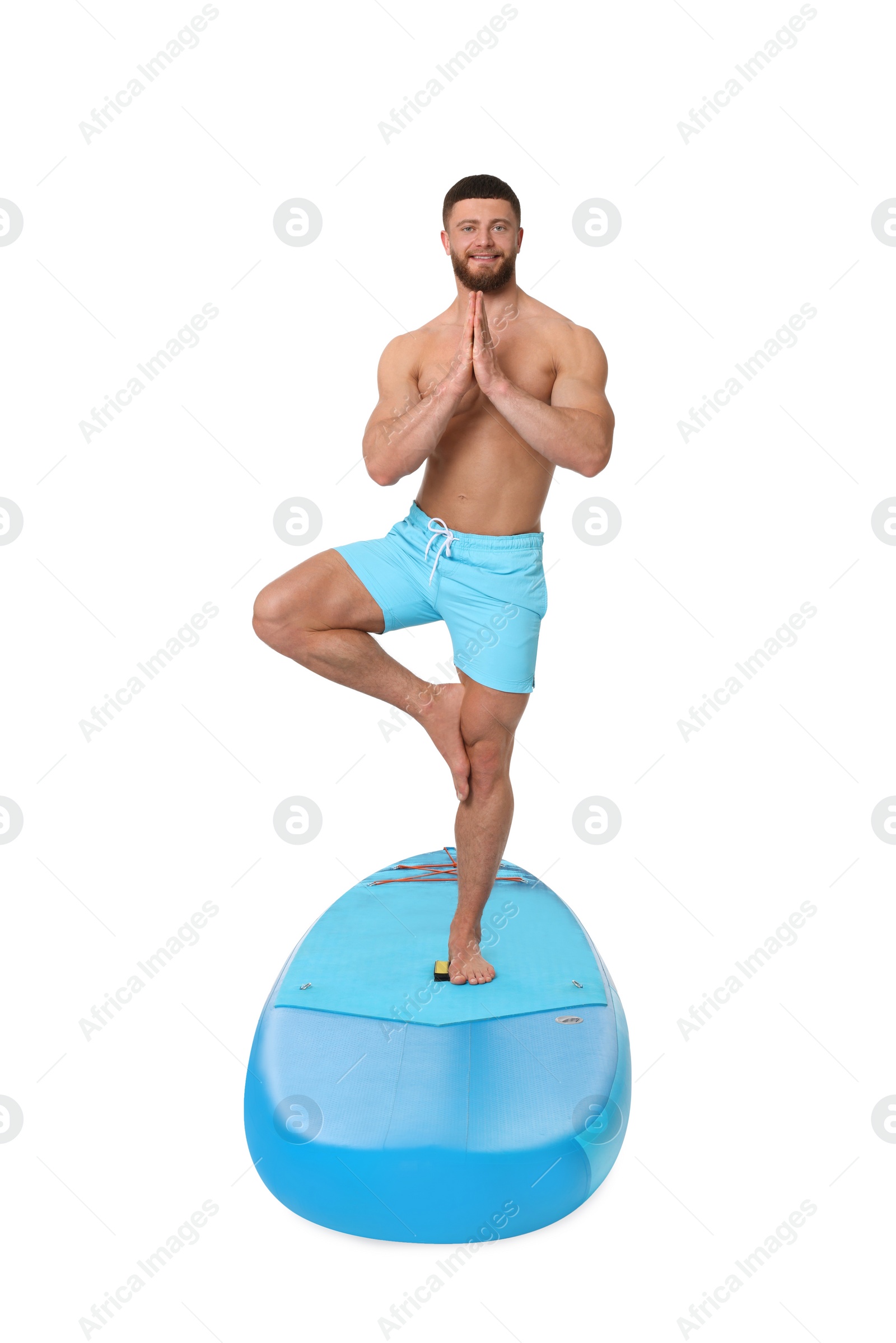 Photo of Happy man practicing yoga on blue SUP board against white background