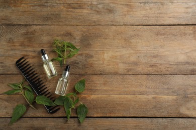 Photo of Stinging nettle extract and comb on wooden background, flat lay with space for text. Natural hair care