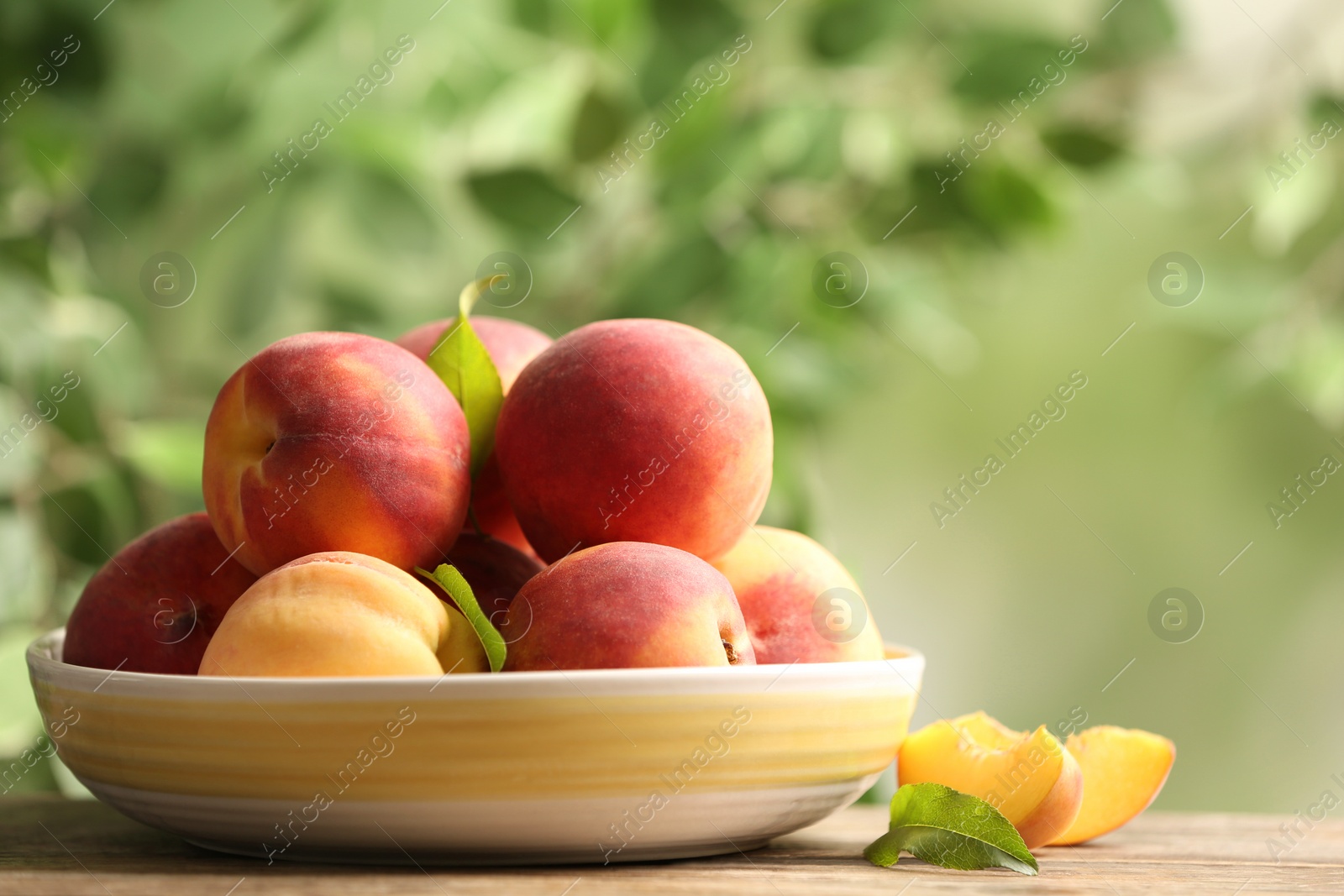 Photo of Fresh sweet peaches on wooden table outdoors