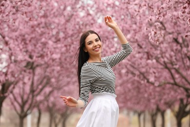 Photo of Pretty young woman in park with blooming trees. Spring look