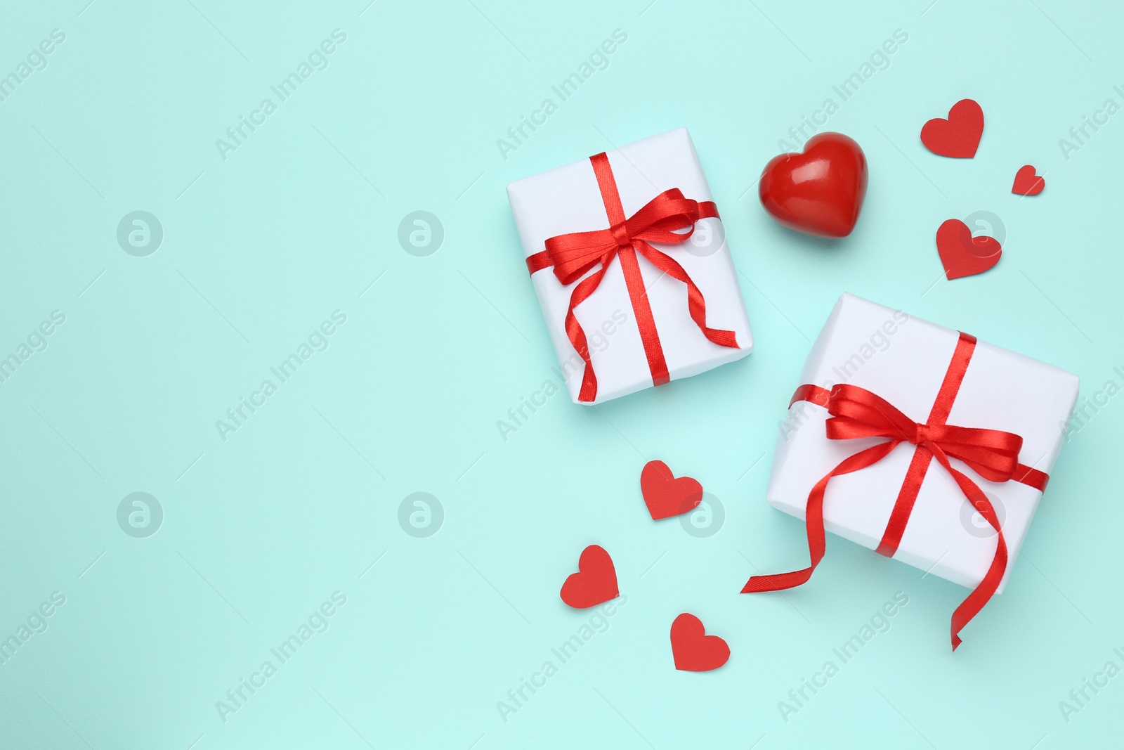 Photo of Gift boxes with decorative red hearts on turquoise background, flat lay. Space for text