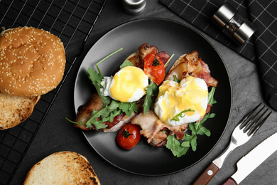 Photo of Delicious eggs Benedict served on black table, flat lay