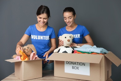 Photo of Young volunteers collecting donations at table on grey background