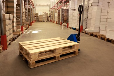 Image of Modern manual forklift with wooden pallets in warehouse