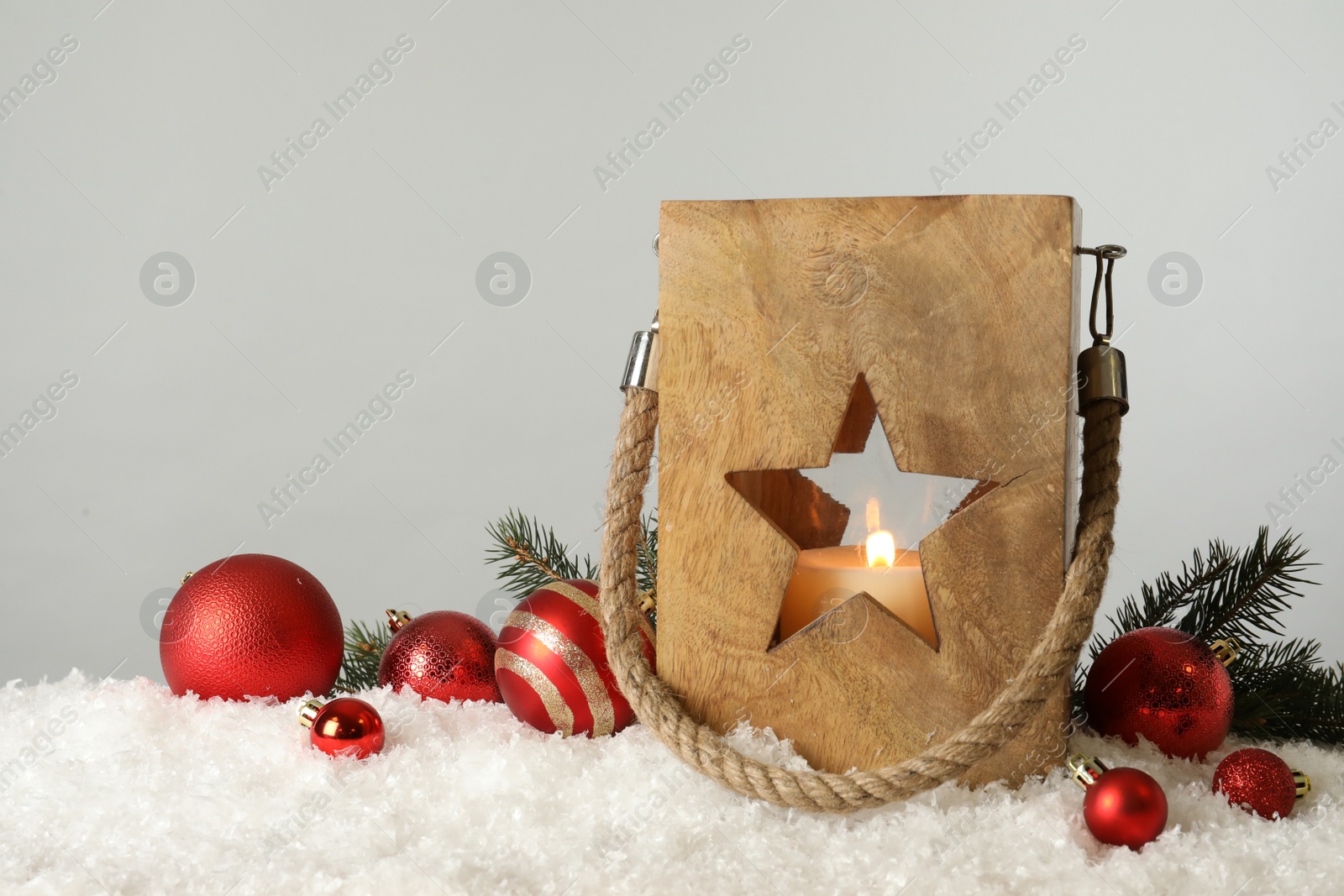 Photo of Composition with wooden Christmas lantern on snow against light grey background, space for text
