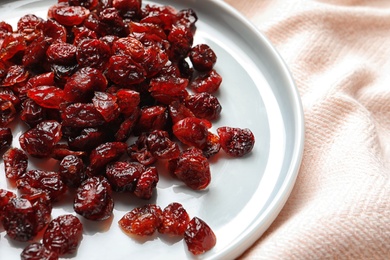Photo of Plate with cranberries on fabric, closeup. Dried fruit as healthy snack
