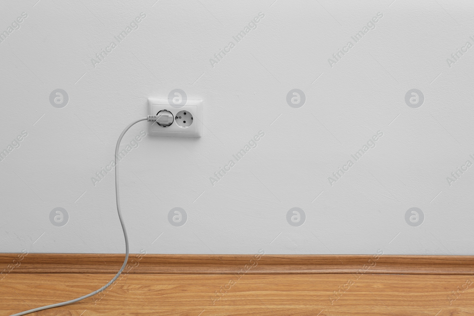 Photo of Power socket and plug on wall indoors, space for text. Electrician's equipment