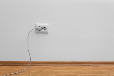 Photo of Power socket and plug on wall indoors, space for text. Electrician's equipment