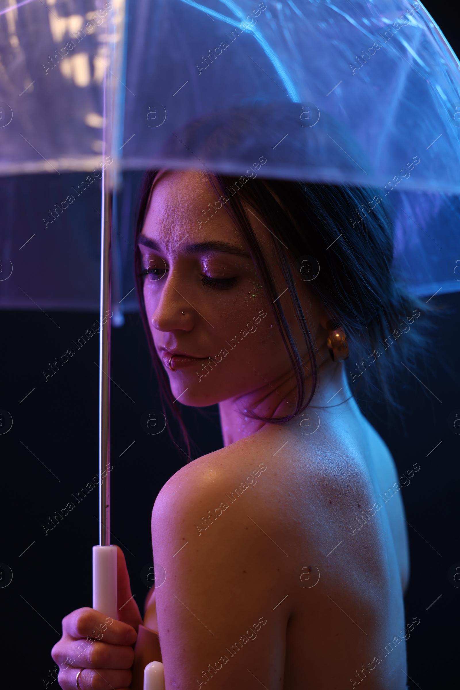 Photo of Beautiful woman with umbrella on dark background in neon lights