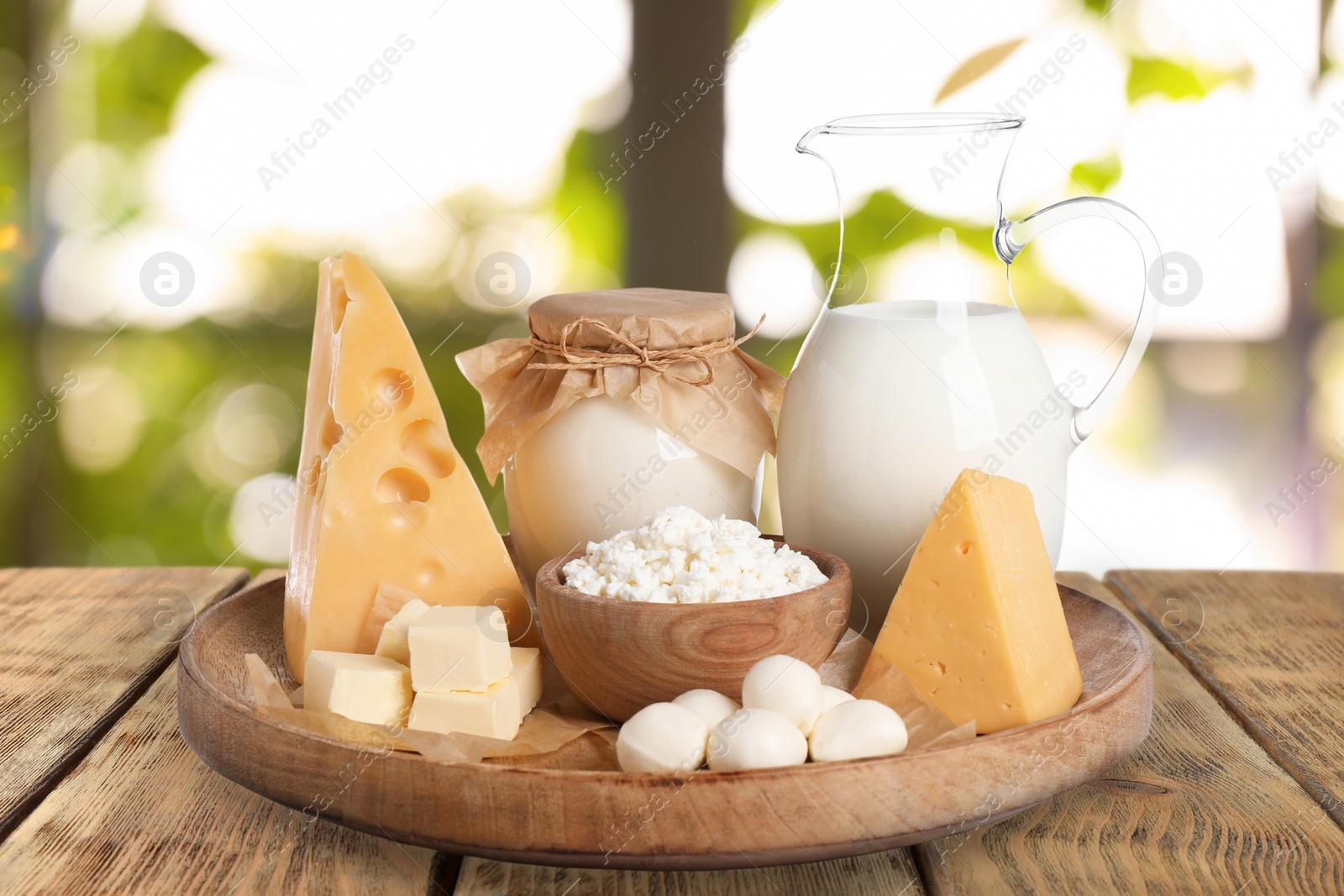 Image of Set of different dairy products on wooden table outdoors