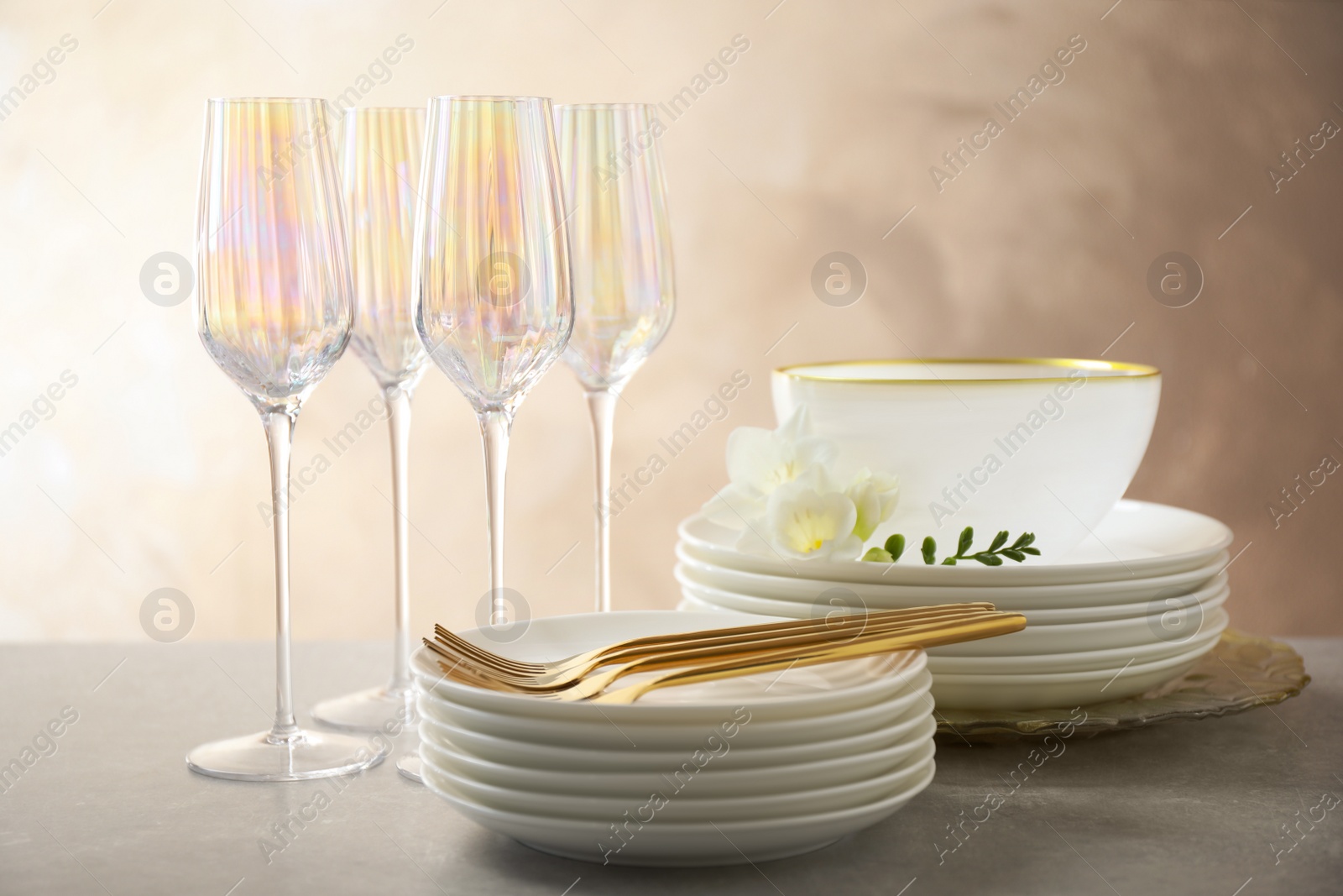 Photo of Set of glasses and dishes with flowers on light grey table