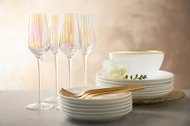 Set of glasses and dishes with flowers on light grey table