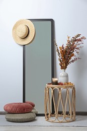 Table, mirror and pillows on floor near white wall