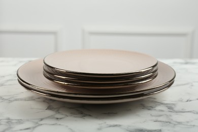 Photo of Beautiful ceramic plates on white marble table indoors, closeup