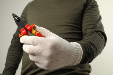 Man with combination pliers on light background, closeup