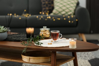 Tea, cookies and decorative elements on wooden table in living room