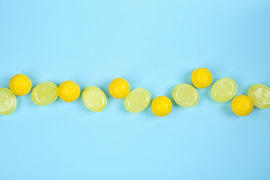 Photo of Delicious lemon candies on light blue background, flat lay