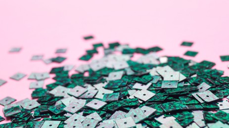 Many beautiful green sequins on pink background, closeup