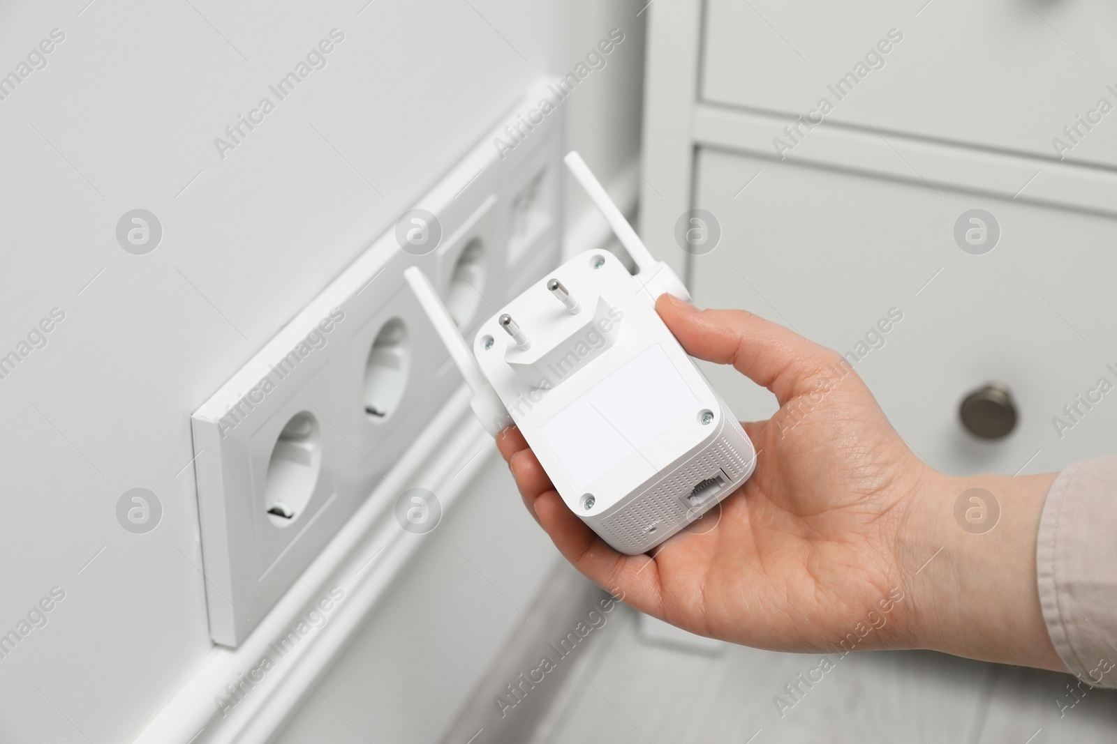 Photo of Woman holding wireless Wi-Fi repeater indoors, closeup