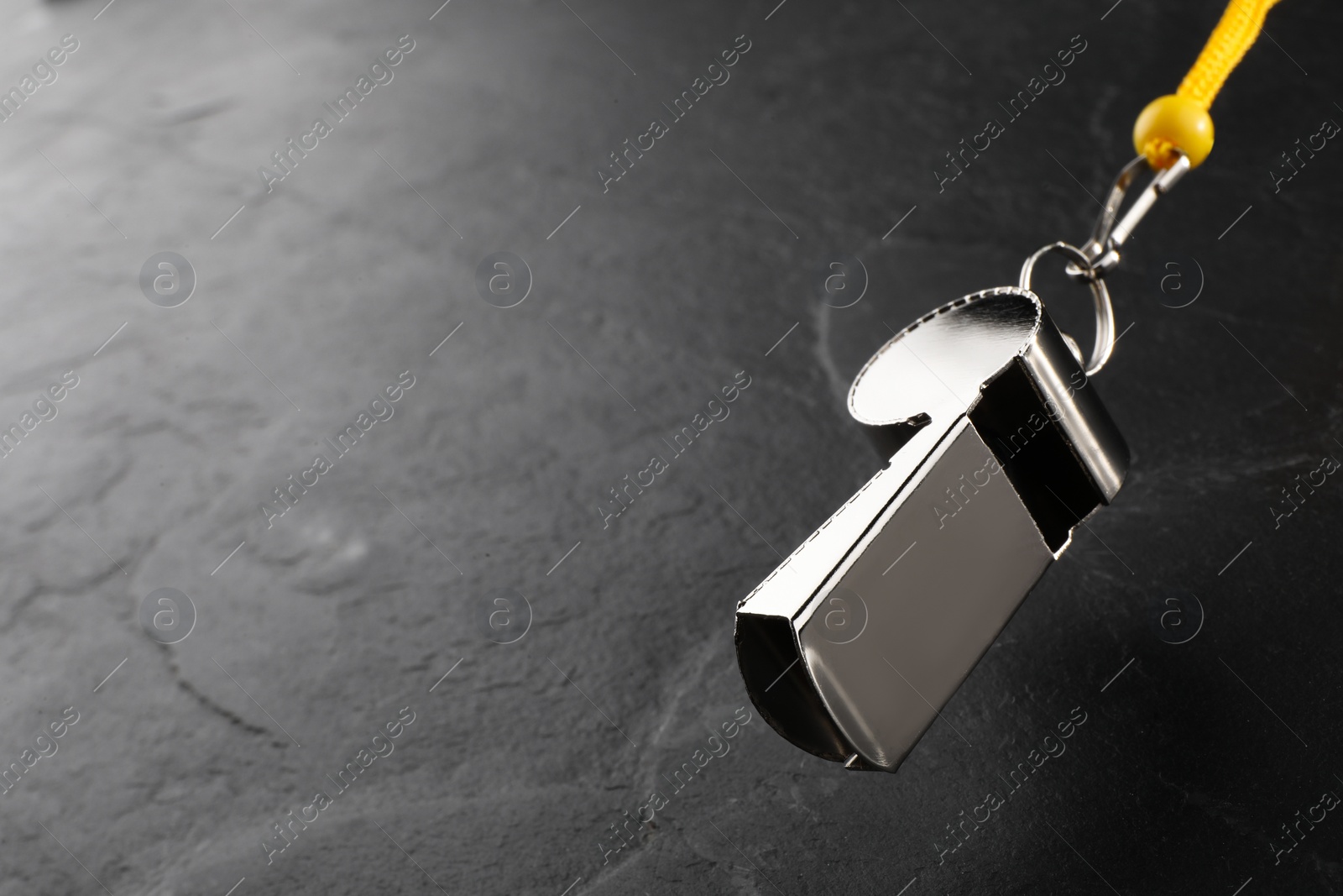 Photo of Referee equipment. Metal whistle on black textured background, closeup and space for text