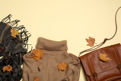 Photo of Flat lay composition with sweater and dry leaves on yellow background, space for text. Autumn season