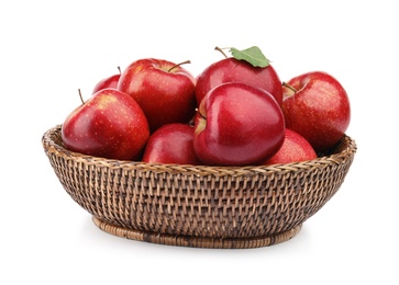 Photo of Wicker bowl of ripe juicy red apples with leaf on white background