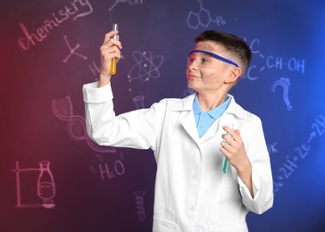 Photo of Schoolboy with test tubes against blackboard with written chemistry formulas