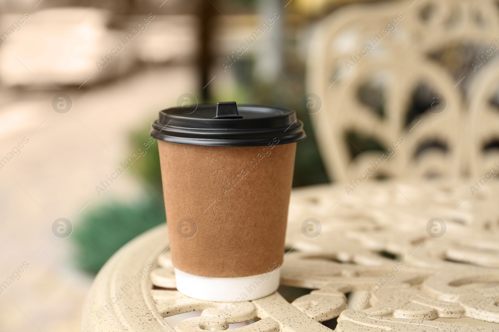 Photo of Paper cup on table in outdoor cafe. Coffee to go