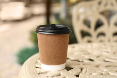 Paper cup on table in outdoor cafe. Coffee to go